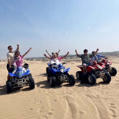 A group of people riding quads in Sidi Kauoki on the beach smiling