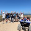 A group of people standing beside a quad in Sidi Kauoki smiling and putting their arms in the air waving