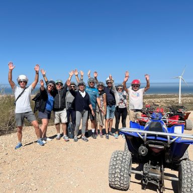 A group of people standing beside a quad in Sidi Kauoki smiling and putting their arms in the air waving