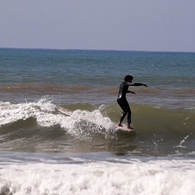 Achoui surfing a wave on hisn long board in Sidi Kaouki