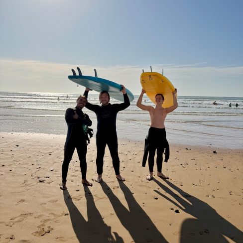 two-Guys taking a surf lesson lesson with Momo in Sidi Kaouki holding their boards beneath theri head