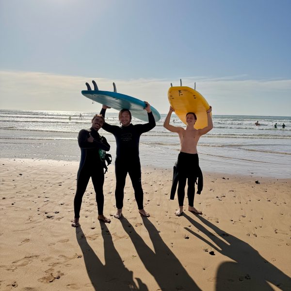 two-Guys taking a surf lesson lesson with Momo in Sidi Kaouki holding their boards beneath theri head